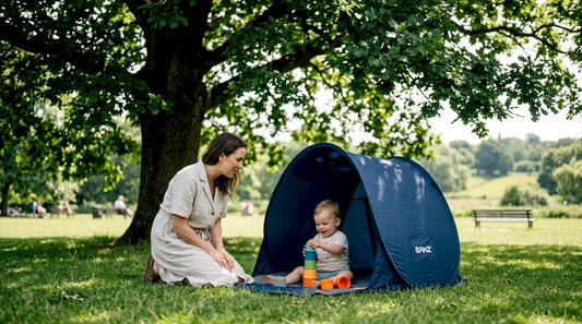 Parent and toddler using sun tent at park